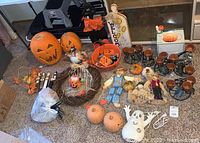 Overview of various fall decor including carved pumpkin decorations, wreath, scarecrows, orange bowl, and candleholders.