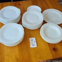 Full set of plates and bowls arranged on wooden table showing different sizes and styles included.