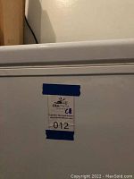 Close up of label on freezer refrigerator chest showing organizer's auction sticker and lot number 012.