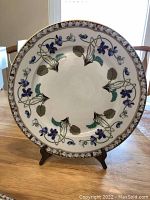 Full view of a dinner plate on a display stand showing floral pattern and brown border