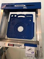 Close-up of Werner branded blue plastic step/platform attached to ladder with aluminum rails.