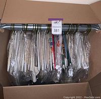 Box full of assorted dry-cleaned linens in plastic protective covers hung on hangers