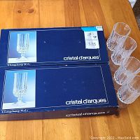 Two unopened boxes containing 6 Cristal d'Arques Longchamp glasses each, with 4 additional loose glasses shown beside the boxes.