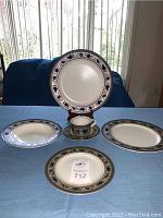 Front view of various pieces laid on table including plates and mug showing decorative border pattern.