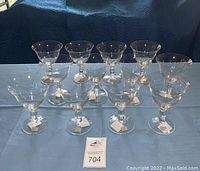 Front view showing 12 clear Mikasa crystal goblets arranged on a cloth surface with price stickers visible on some bases.