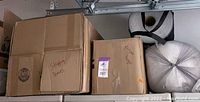 Boxes labeled for packing with paper bags and bubble wrap in a garage setting.