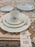 Single place setting showing stacked dinner plate, salad plate, bread plate, shallow soup bowl, cup and saucer with pattern visible