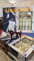 Five boxed sets of Tools of the Trade stainless flatware on a table, showing original packaging.