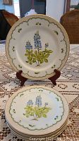 Dinner and salad plates featuring blue Lupines floral design with gold scalloped edge and green accents.