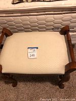 Top-down view of the cushioned seat showing beige diamond pattern upholstery and wooden frame with curved arms and turned legs.