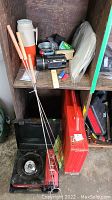 Full view of camping accessories on shelf including cooking stove, roasting sticks, thermos, flashlight, citronella candle, and more.