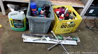 Wide shot showing two crates with assorted car care products and two packaged windshield wipers laid out with a 4-way cross wheel wrench in front.