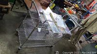 Side view of metal rolling cart showing two shelves and one handle side