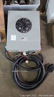 Front view of gray metal enclosure with rotary dial and attached power cord.