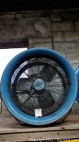 Front view of blue cylindrical barrel fan with protective wire guard