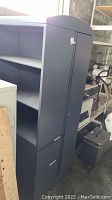 Photo showing the metal locker system with three open shelves and two filing drawers in a dark gray finish.
