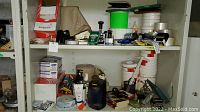 Shelves with various office supplies including tapes, boxes, bottles, and the electric pencil sharpener.
