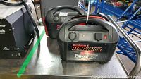 Two Motomaster Eliminator Power Boxes side by side on a metallic surface, showing front control panels and handles on top.