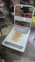 Full view of the rolling cart showing platform base, foldable handle, and surface rust