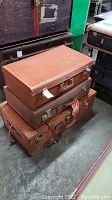 Stack of three vintage suitcases showing varying sizes and colors