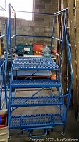 Front view of blue rolling workspace platform ladder showing four steps and guard rails.