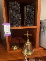 Two African ebony carved bookends, brass candle holder, and sailor themed brass bell