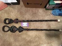 Two ebony walking sticks laid side by side on carpet showing full length and white caps.