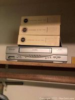Emerson VCR and Kodak Carousel Slide Trays stacked on a wooden shelf