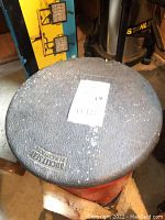 Closed view of metal fishing tub lid labeled 'Buckmaster by Morrell' with wear and chipping paint.