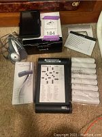 Garmin GPS with headphones, luggage scale, crossword puzzle device and extra rolls spread out on carpet
