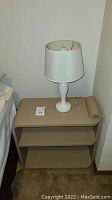 Full view of night stand with lamp placed on top, showing overall shape, color, and condition.