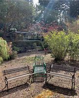 Two wood and metal outdoor benches positioned parallel to each other with a green metal outdoor chair centered between them in an outdoor yard setting.