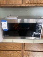 Front view of Panasonic inverter microwave oven in stainless steel with large glass door installed in kitchen cabinetry.