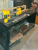 Full view of lathe on stand with chisels, jig, wood blanks