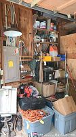 Wide view of shelving unit loaded with items including cords, boombox, plastic bin, power tool