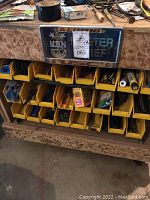 Wooden cart with 24 yellow trays filled with small tools and parts, with a decorative U.S. Navy plaque on the top front of the cart
