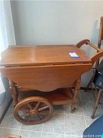 Side view of wooden bar cart showing large wooden wheel and handle