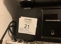 Photo of Denon AVR-1513 AV Stereo Receiver showing front panel with controls and branding sticker.