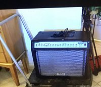 Black folding cart with metal frame and handle, folded flat for easy storage or transport.