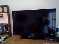 Front view of Sony 28 inch flat panel TV with black bezel and remote control on base.