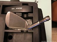 Close-up of iron club head labeled 'Tour Model 609' showing grooved metal face and shaft connector.