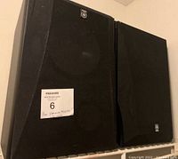 Photo showing pair of black Yamaha NS-6420 stereo speakers with front grills, placed on a shelf.
