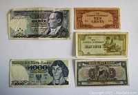 Five banknotes laid out flat showing front sides of each, different countries and denominations.