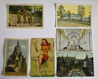 Six vintage postcards laid out on white surface showing varied themes from architecture to illustration.