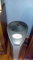 Full view of black tower-style Vornado air purifier showing fan outlet on top and overall shape.