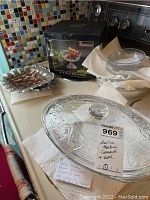Anchor Hocking casserole with lid, boxed 9-inch footed glass bowl, glass salad set, and silvered metal trays arranged on kitchen counter.