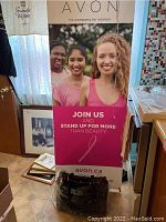 Photo showing Avon collapsible banner with three women, slogan and Avon web address, banner displayed fully upright.