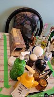 Photo of various Avon collectible bottles shaped like men's items arranged on a table including pipes, pump bottles, golf ball bottle, and others.