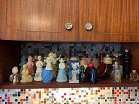 Shelf displaying multiple vintage Avon collectible cologne bottles in various colors and shapes including figurines and traditional bottle shapes