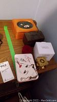 Overview of all items including wood jewelry boxes, Mikasa box, floral tin and brass dice